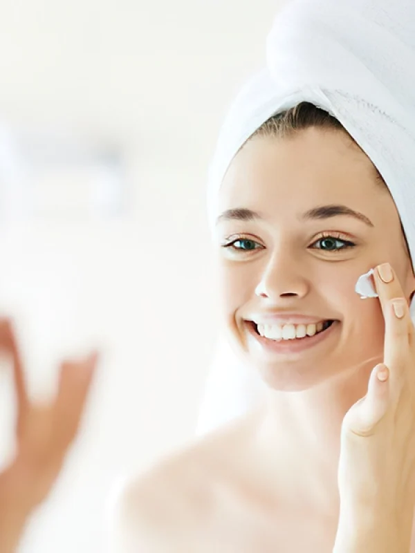 Chica sonriendo mientras aplica crema en la cara para apollo de la entrada de junio, El envejecimiento de la pie.